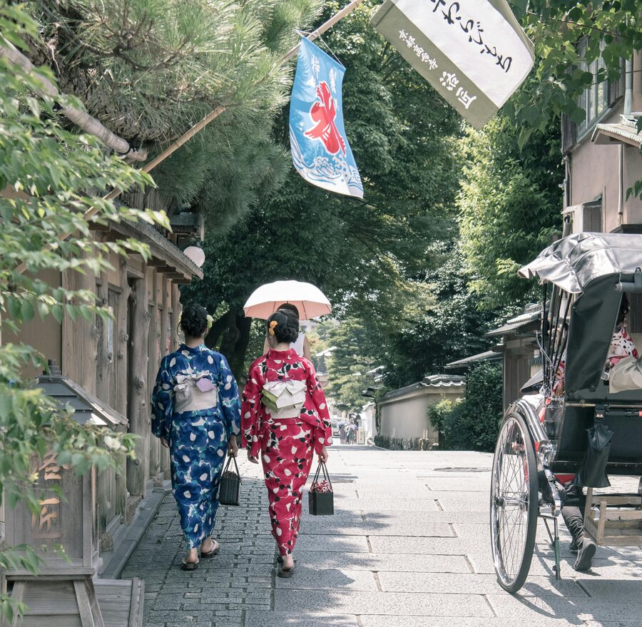 Two people in summer yukata walking through a Kyoto street