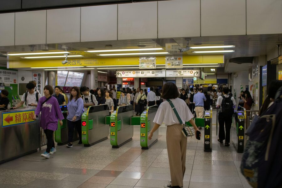 A hand holding a Suica IC transit card at a Tokyo train ticket gate