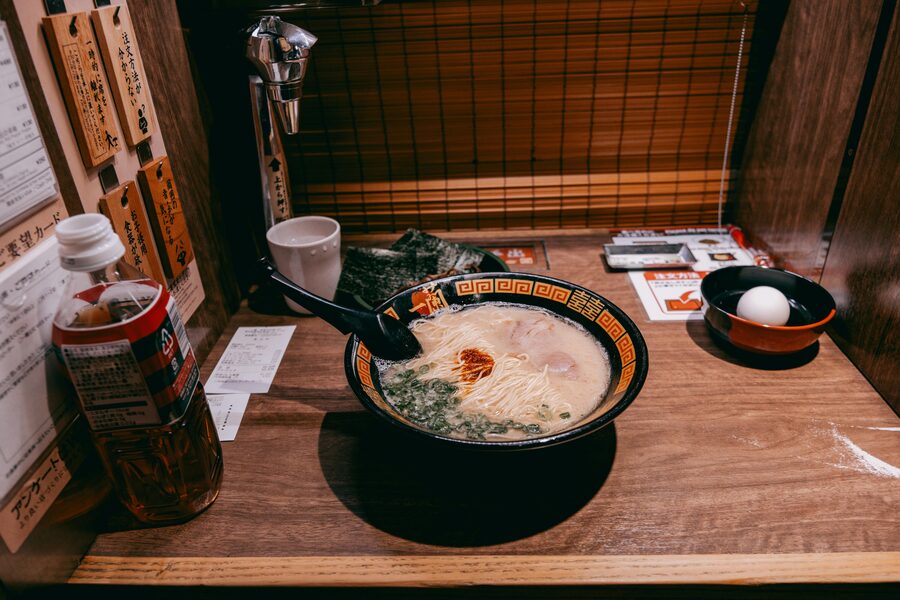 A close-up bowl of tonkotsu ramen with chashu pork, scallions and a soft egg